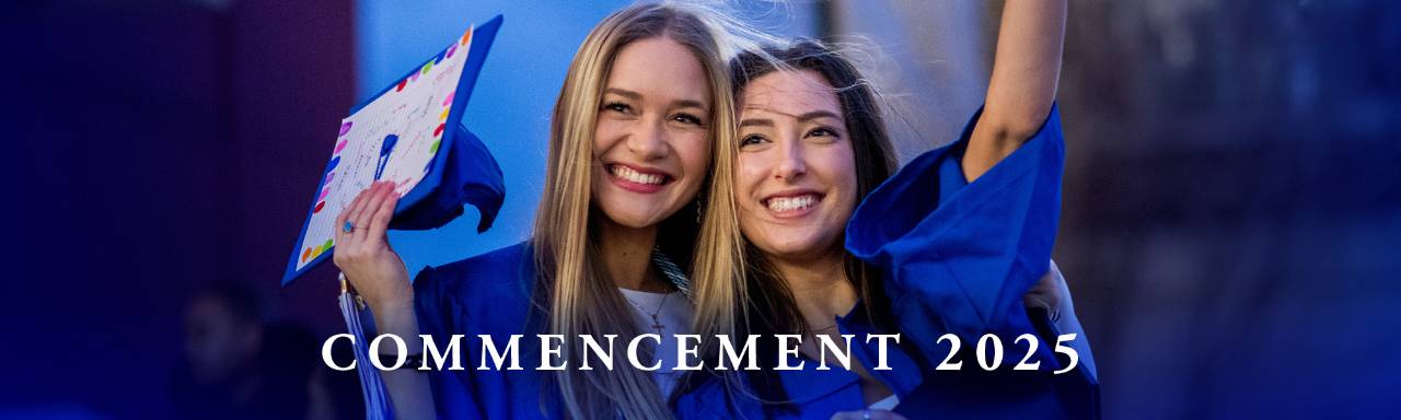 two graduates in blue cap and gowns smiling